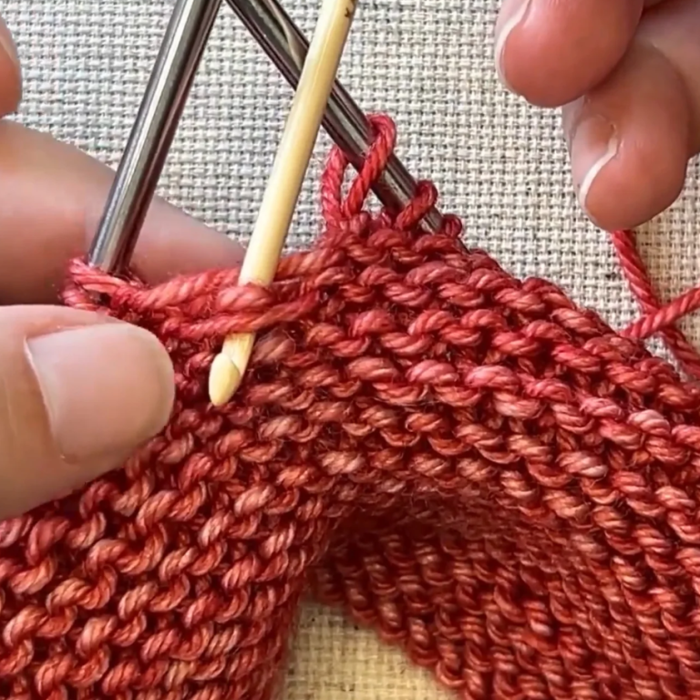 Hands knitting with red yarn.